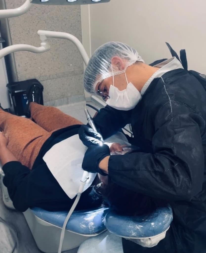 Cirurgião-dentista em atendimento, usando caneta de alta rotação